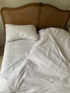 White pillowcase on a bed with a brown headboard